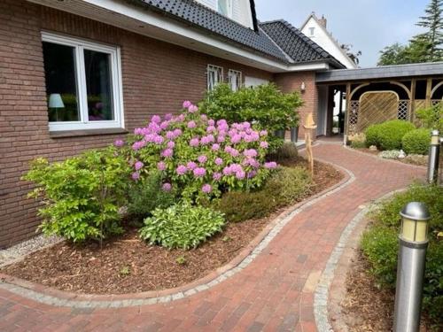 a house with pink flowers and a brick driveway at Haus Antje in Scharbeutz