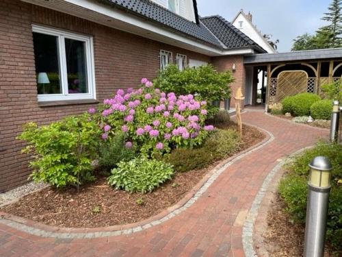 シャルボイツにあるHaus Antjeのピンクの花とレンガの私道のある家