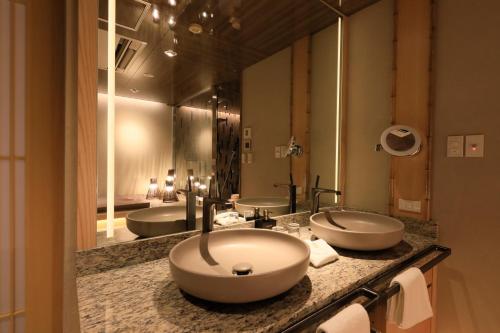 a bathroom with three sinks and two mirrors at Hotel Gion Ichirin in Kyoto