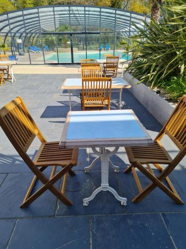 - une table de pique-nique et des chaises avec une table et une piscine dans l'établissement Hôtel du Golf Saint-Laurent, à Ploemel
