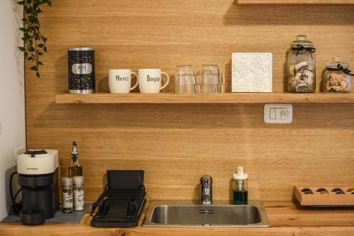 a kitchen counter with a sink and cups on a shelf at Stunning Modern Studio in Netanya minutes from the beach by Sea N' Rent in Netanya