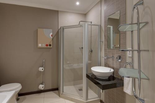 a bathroom with a shower and a toilet and a sink at Protea Hotel by Marriott Cape Town Durbanville in Bellville