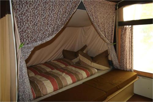 uma cama numa tenda num quarto em DDR Klappfix "FAMILIENPALAST" direkt am Strand em Dranske