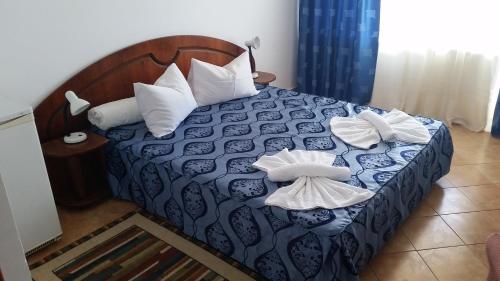 a bedroom with a blue and white bed with white pillows at Hotel Forum in Costinesti