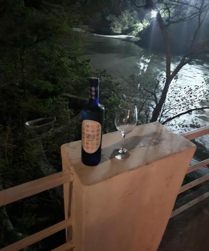 a bottle of wine and a wine glass on a fence at Samira's Birds & Butterflies Park-Spashram Ganga Beach Retreat in Rishīkesh