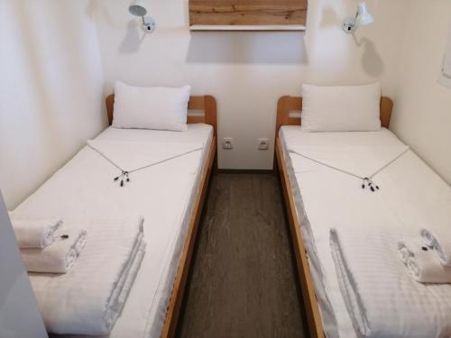Dos camas en una habitación pequeña con sábanas blancas. en Camping Cremona Turanj, en Turanj