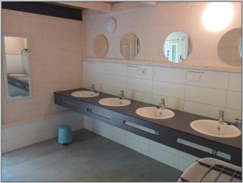 a bathroom with three sinks and two mirrors at DDR Klappfix "FAMILIENPALAST" direkt am Strand in Dranske