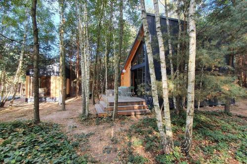 una casa en el bosque con un banco delante en Szumi Las, 