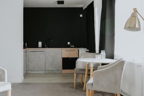 una cucina con tavolo, sedie e parete nera di Silesia Apartments a Katowice