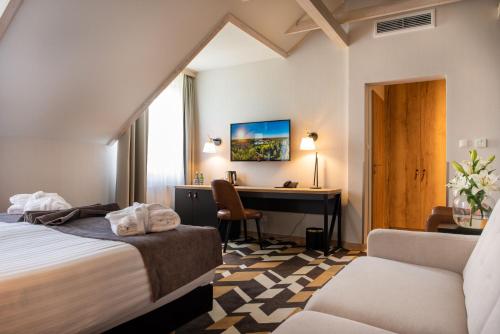 a hotel room with a desk and a bed at Santa Natura Resort & SPA in Nowa Wieś