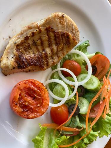a plate of food with a piece of meat and a salad at The Gallery Hotel Nai Harn in Nai Harn Beach