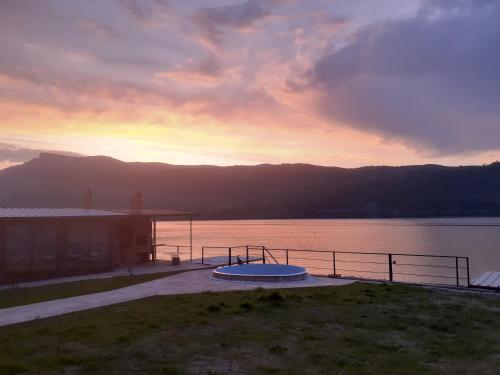 a sunset over a body of water with a house at Cazanele Dunarii "La Cumatru" in Dubova