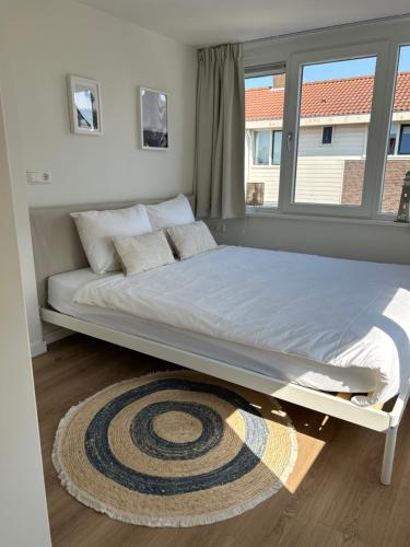 a large bed in a room with a window at Paris Plage - volledig vernieuwd, free parking in Noordwijk aan Zee