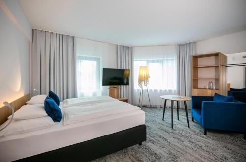 Habitación de hotel con cama y silla azul en ARCOTEL Wimberger Wien, en Viena