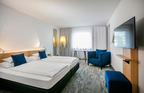 una habitación de hotel con una cama grande y una silla azul en ARCOTEL Wimberger Wien, en Viena