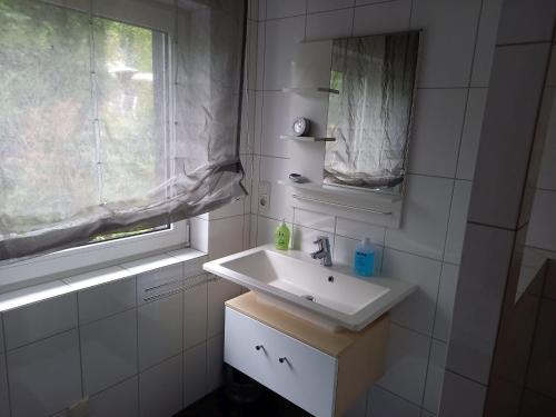 La salle de bains blanche est pourvue d'un lavabo et d'une fenêtre. dans l'établissement Ferienwohnung Oerder, à Meinerzhagen