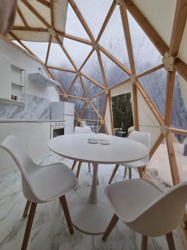 Un comedor con una mesa y sillas blancas. en Lodges des Grands Chênes, en Andelarrot