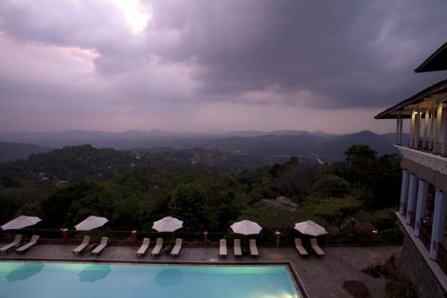 a swimming pool with chairs and umbrellas on top of a building at Amaya Hills Kandy in Kandy