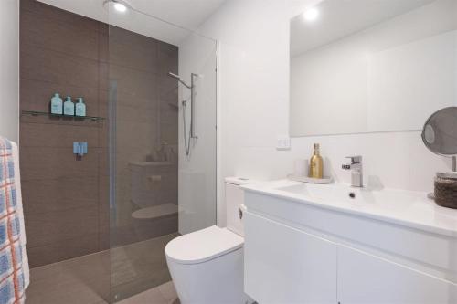 a bathroom with a toilet and a sink and a shower at Husky Sol in Huskisson