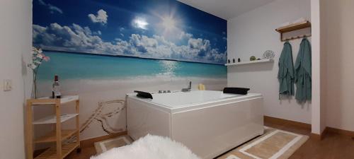 La salle de bains est pourvue d'une baignoire blanche avec une fresque murale représentant l'océan. dans l'établissement Casa Airen con jacuzzi, à Miguel Esteban