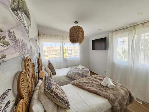 a bedroom with two beds and a couch and a tv at La Sardina de Denia in Denia