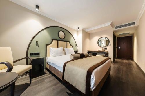 イスタンブールにあるホテル イギタルプ イスタンブールのベッド、テーブル、椅子が備わるホテルルームです。