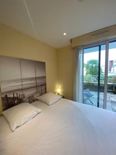 une chambre avec un grand lit blanc et une fenêtre dans l'établissement Nouveau monde, à La Rochelle