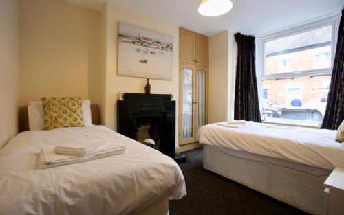 een slaapkamer met 2 bedden, een open haard en een raam bij Albemarle House in Taunton