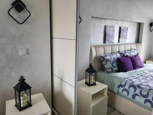 Schlafzimmer mit einem Bett mit lila Kissen und einem Spiegel in der Unterkunft Chic and Cozy Apartment on the Main Pedestrian Street in Struga