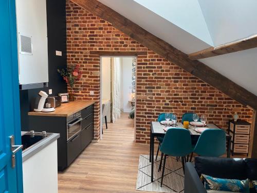 une cuisine avec un mur en briques, une table et des chaises dans l'établissement Le Grenier de la Tour d'Auvergne CV, à Rennes