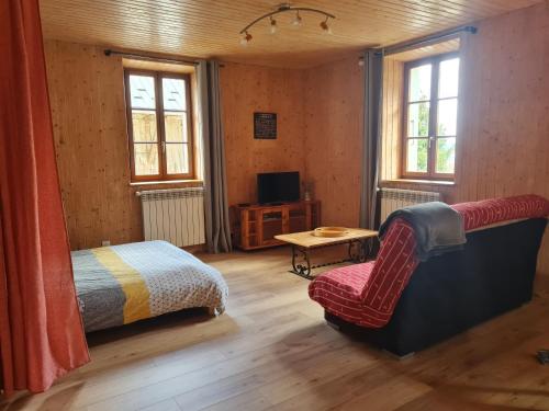 Schlafzimmer mit einem Bett, einem Stuhl und Fenstern in der Unterkunft Aux P'tioux Bonheurs in Le Noyer