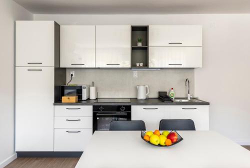a kitchen with white cabinets and a bowl of fruit on a table at Apartment Fani with free private parking in Dubrovnik