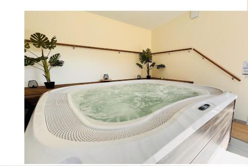 bañera grande en una habitación con plantas en Au Petit Vivoin en Vivoin