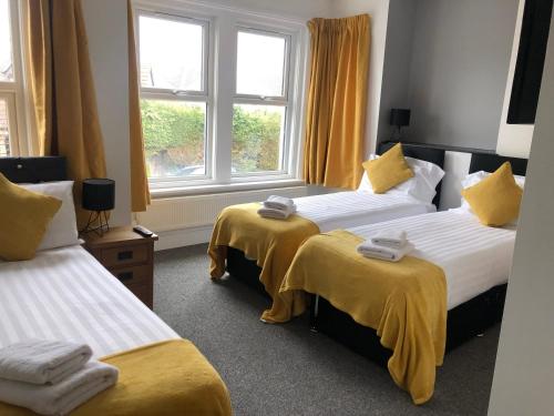 a room with two beds with yellow sheets and a window at Stylish and spacious Southampton stay in Southampton