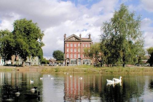 un gran edificio de ladrillo rojo con cisnes en un lago en Barnes the village in the centre of London, en Londres