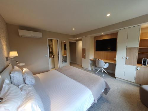 1 dormitorio con 1 cama blanca grande y escritorio en Hôtel The Originals Résidence de Rohan (EX RELAIS DU SILENCE), en Vaux-sur-Mer