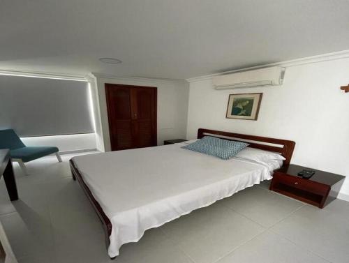 ein Schlafzimmer mit einem großen Bett und einem Stuhl in der Unterkunft Rivas Apartamentos Cartagena in Cartagena de Indias