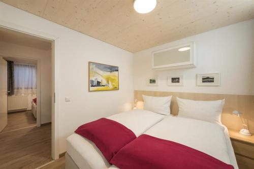 Schlafzimmer mit einem großen weißen und roten Bett in der Unterkunft Ferienwohnungen Nachbaur in Oberjoch