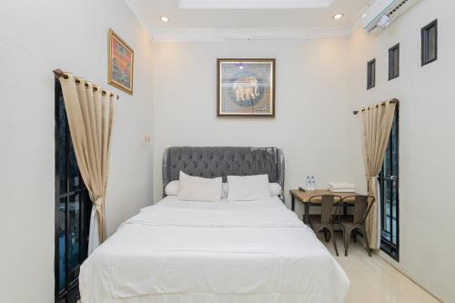 een slaapkamer met een wit bed en een bureau bij Boss Residence Serang Mitra RedDoorz in Kumprung