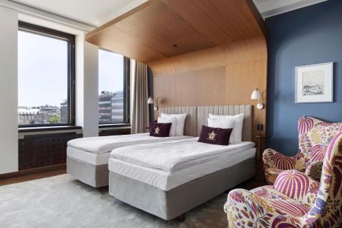 a hotel room with two beds and a chair at Original Sokos Hotel Vaakuna Helsinki in Helsinki