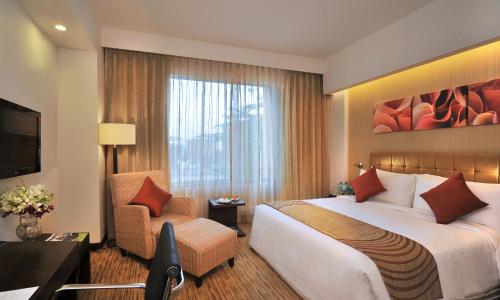 um quarto de hotel com uma cama grande e uma cadeira em Four Points by Sheraton Hotel and Serviced Apartments Pune em Pune