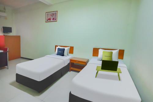 a bedroom with two beds and a chair at Urbanview Hotel Bartu Moh Toha Bandung by RedDoorz in Bandung