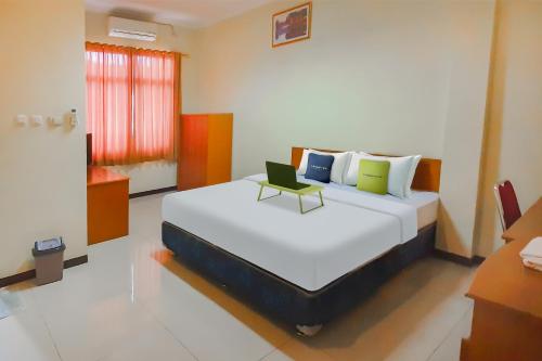 1 dormitorio con 1 cama con ordenador portátil en Urbanview Hotel Bartu Moh Toha Bandung by RedDoorz, en Bandung