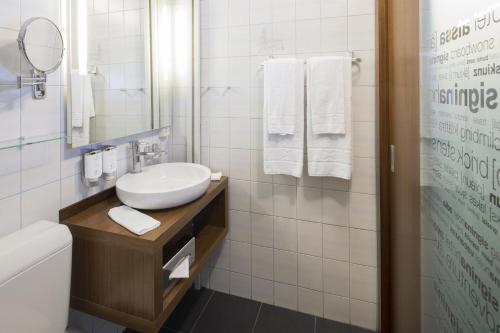 a bathroom with a sink and a toilet and a mirror at signinahotel in Laax