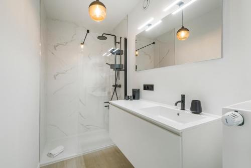 een witte badkamer met een wastafel en een douche bij Maison Madison Nieuwbouw, terras, privé parking! in Middelkerke