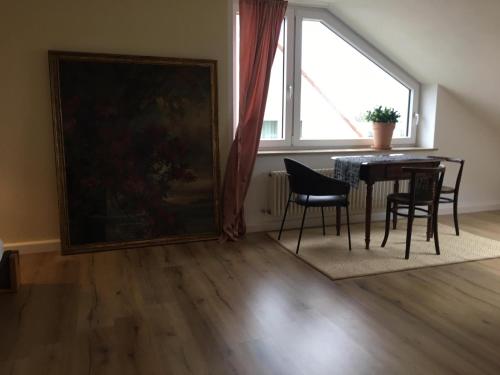 a dining room with a table and chairs and a window at WUNDERBAR. Über den Dächern in Markdorf