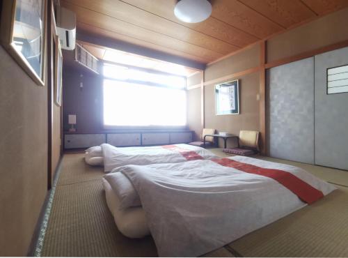 心遊亭ー敬華の間Shin Yu Tei في كانازاوا: سريرين في غرفة مع نافذة كبيرة