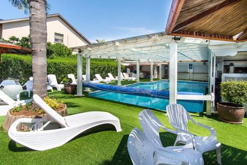 a backyard with white chairs and a swimming pool at Nof glili Mansion in Yavneʼel