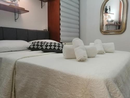 a large white bed with white pillows and a mirror at La casa di Lo, marina di Sorso in Sorso