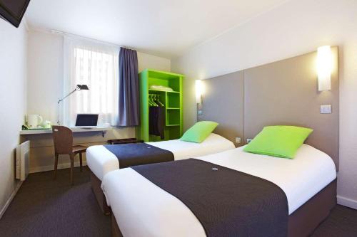 a hotel room with two beds and a desk with a computer at Campanile Saint-Quentin-En-Yvelines in Montigny-le-Bretonneux